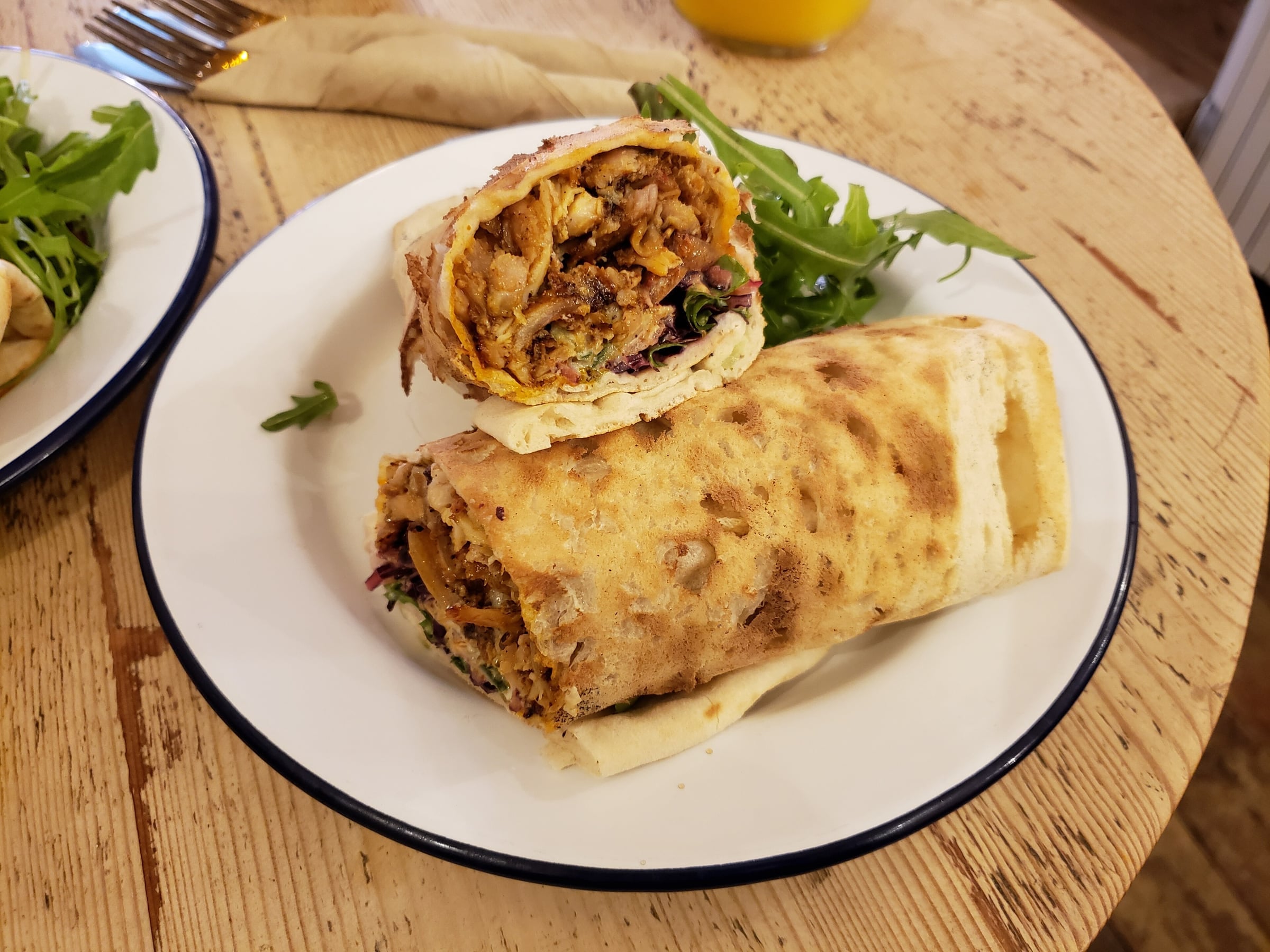 A chicken shawarma wrap cut in half on a plate, showing the filling of chicken and salad