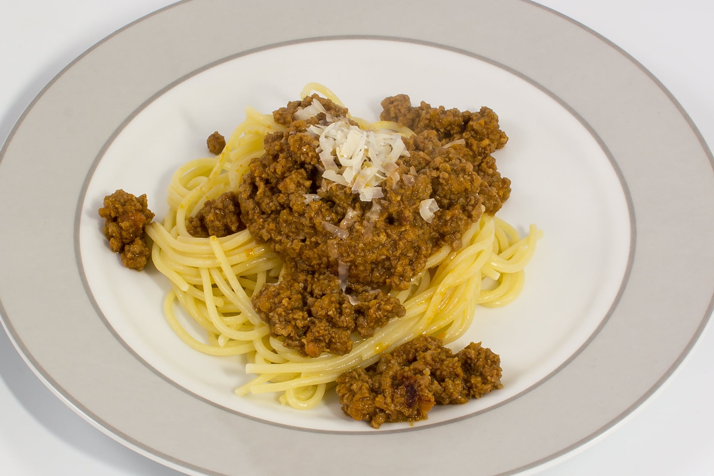 A plate of spaghetti topped with a thick beef and tomato sauce and grated cheese